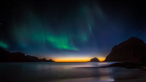 Free Capture of the Northern Lights above a serene coastal landscape in Lofoten Islands, Norway. Stock Photo