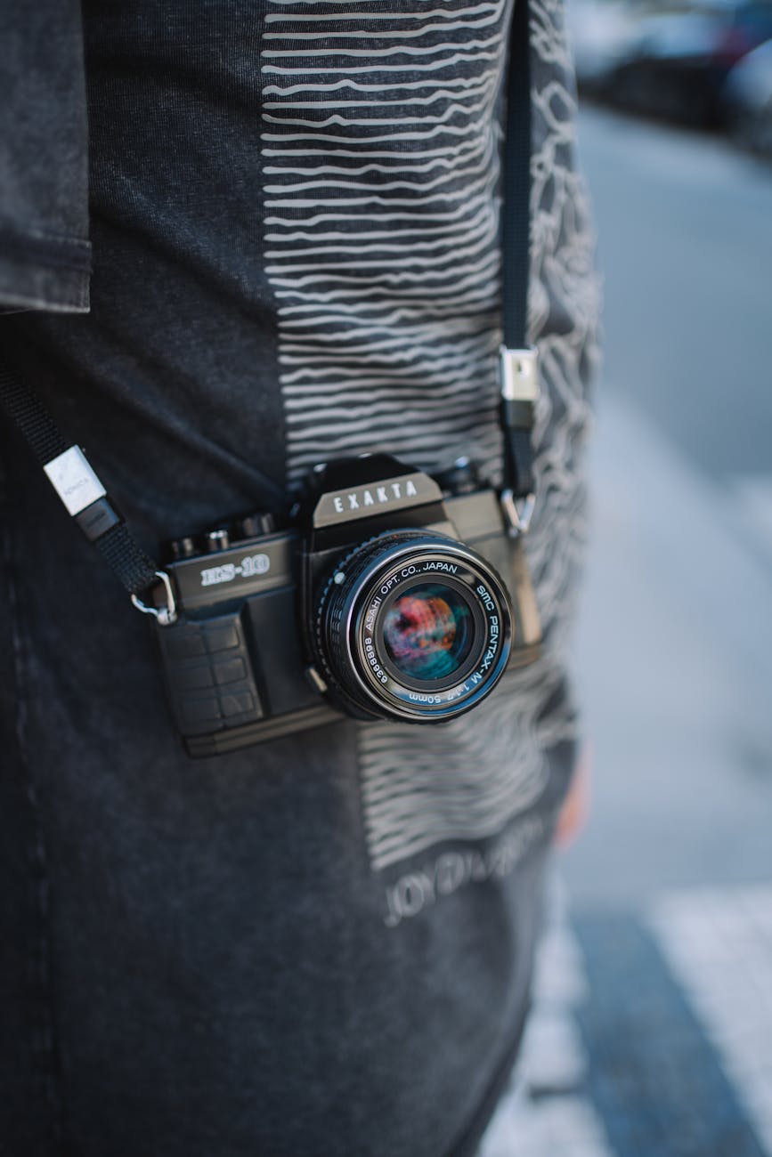 Detailed shot of a vintage Exakta camera hanging by a strap, outdoors.