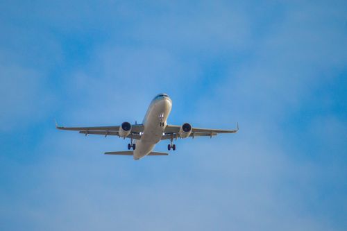 Free A commercial airplane flying high against a clear blue sky, seen from below. Stock Photo