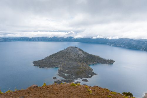 Free Scenic view of Wizard Island in Crater Lake National Park with fog and cloudy skies. Stock Photo