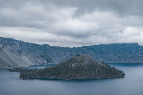 Free Peaceful capture of Wizard Island surrounded by waters and foggy mountains in Crater Lake National Park, Oregon. Stock Photo