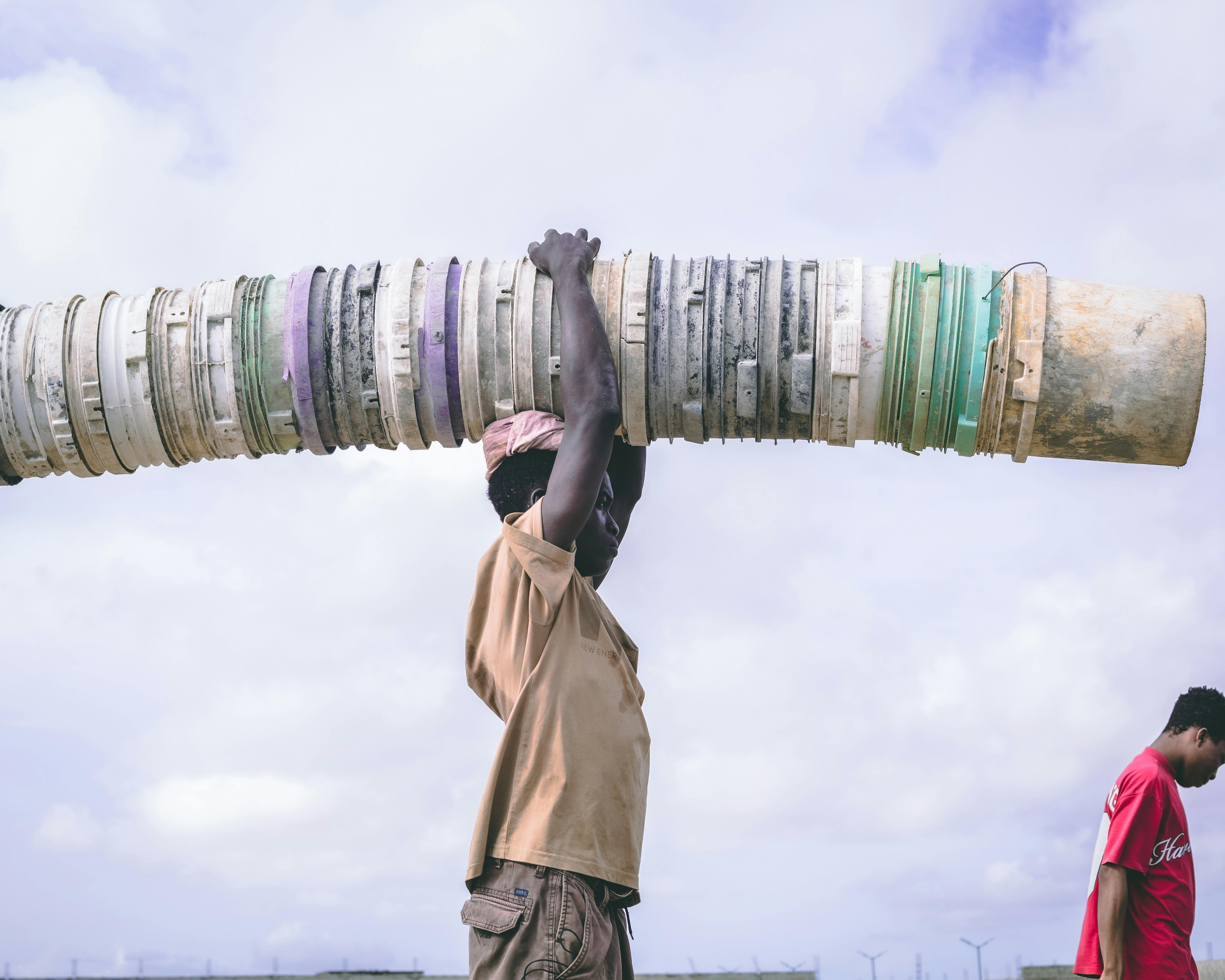 Man carrying large pipe outdoors in rural setting