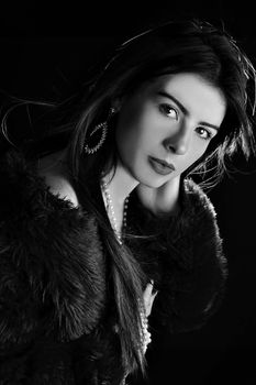 Sophisticated black and white portrait of a woman in a fur coat with jewelry.