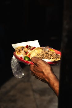 A hand holding a plate of authentic Mexican street tacos in vibrant Mexico City.
