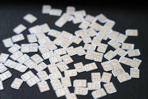 Free A variety of SIM cards scattered on a dark surface, highlighting mobile technology. Stock Photo