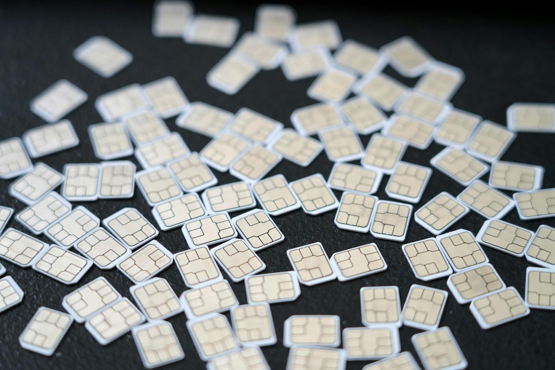 Pile of SIM Cards on Dark Surface in Studio