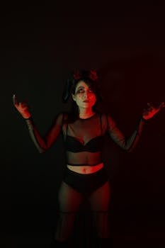 A woman in gothic costume poses with dramatic red lighting, evoking a mysterious atmosphere.