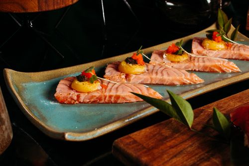 Free A plate of salmon sashimi elegantly presented with garnishes on a ceramic dish. Stock Photo