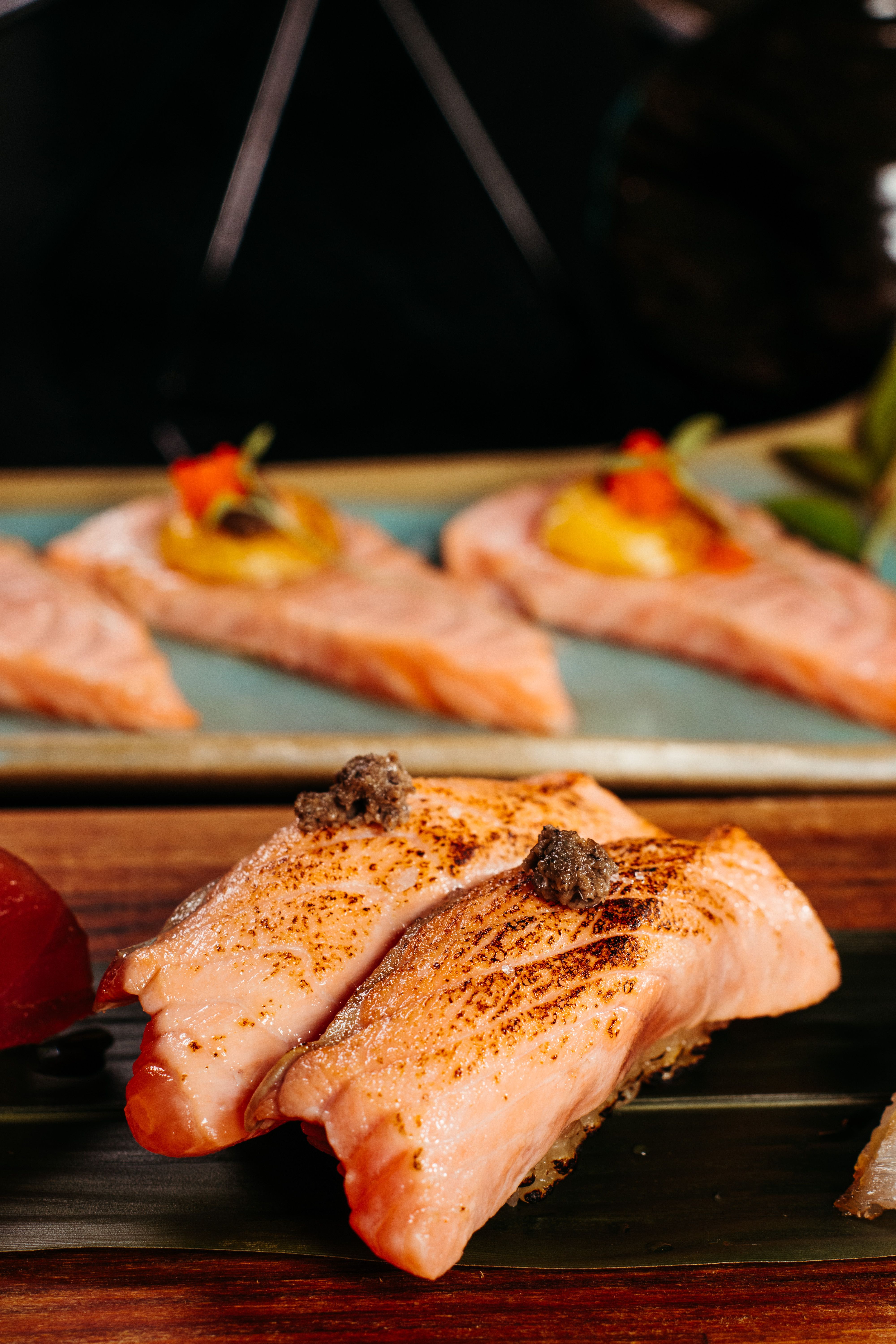 A close-up of delicious grilled salmon pieces with garnish on a wooden platter.
