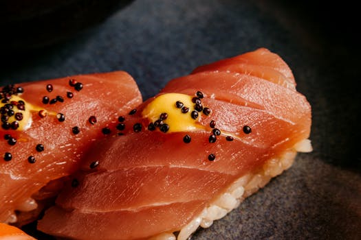 Appetizing close-up of tuna nigiri sushi garnished with mustard and black roe.