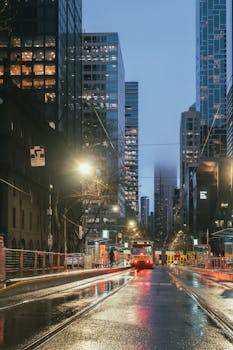A rainy evening street scene in Melbourne, Australia with trams and reflections.