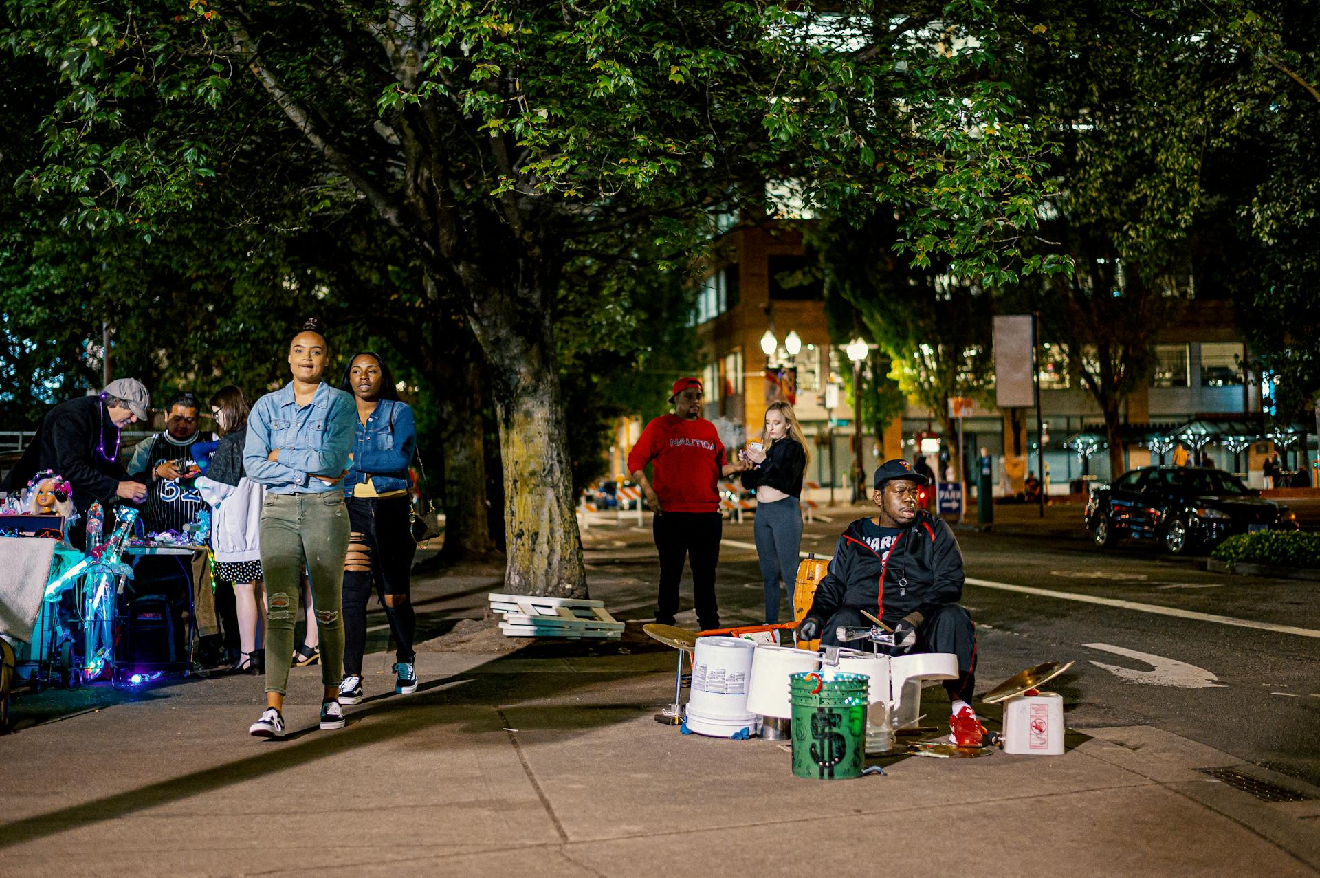 Diverse group of people enjoying a lively night on a city street with street vendors and musicians.