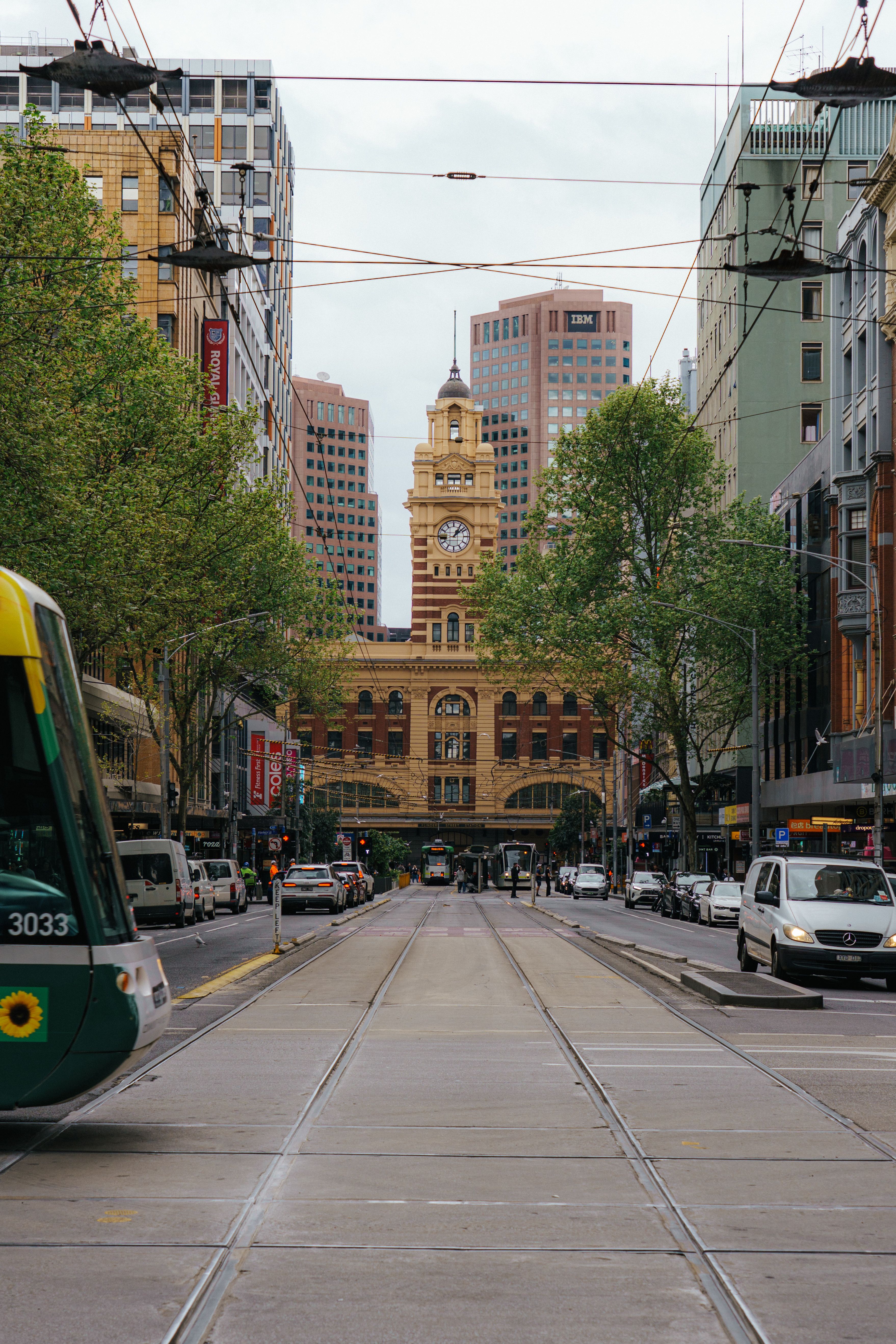 A bustling street scene with tramlines and Flinders Street Station in Melbourne, Australia.