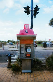 A vibrant Telstra payphone in Apollo Bay, Australia, against a busy street backdrop on the Great Ocean Road.