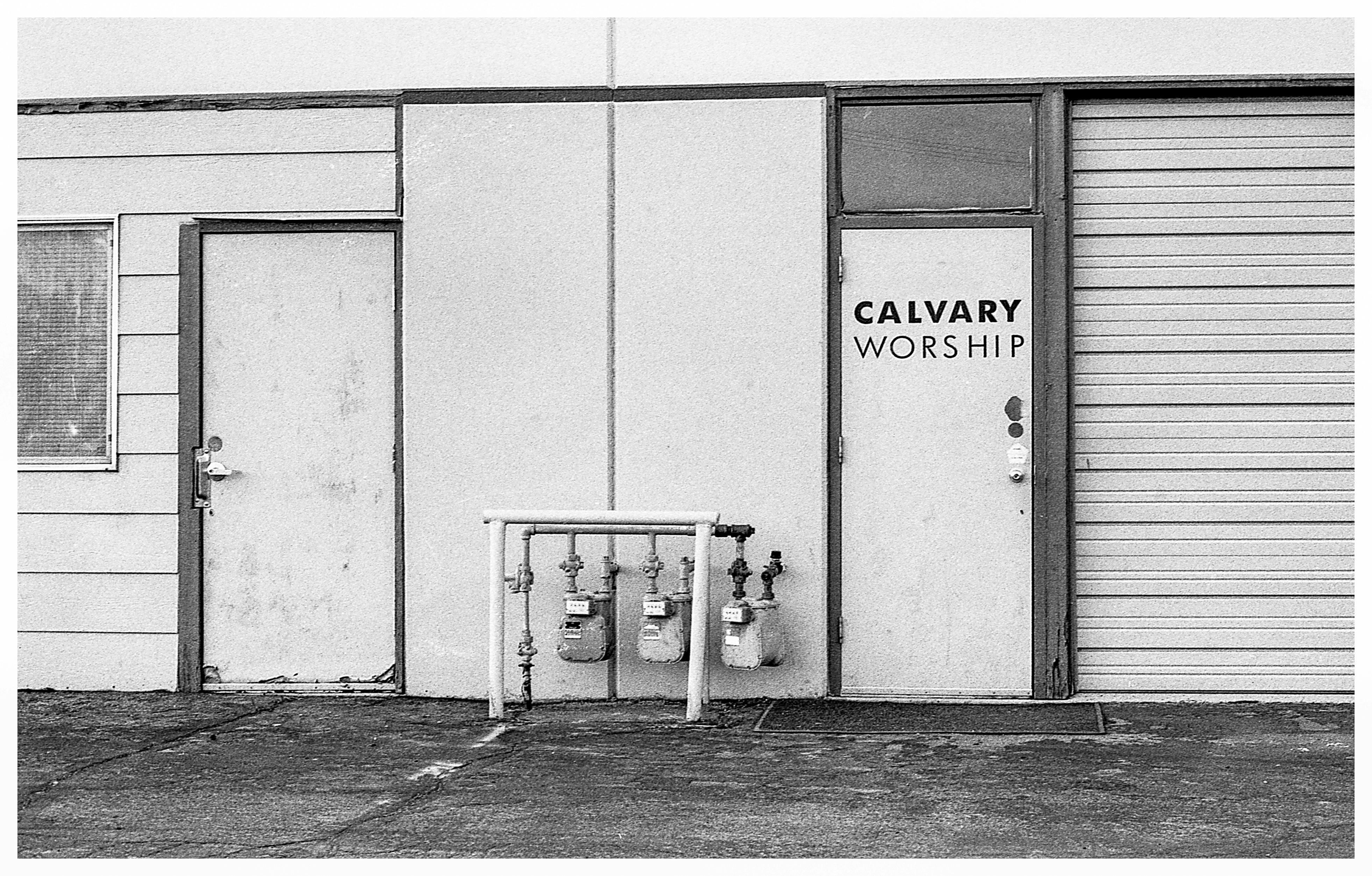 一张复古黑白照片，展现了加略山崇拜建筑的外观，上面有门和煤气表