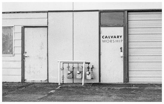 一张复古黑白照片，展现了加略山崇拜建筑的外观，上面有门和煤气表