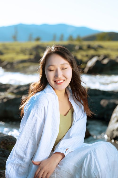 Free Joyful woman in nature with closed eyes by a river, enjoying the sunny day outdoors. Stock Photo