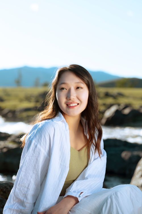 Free A woman enjoying a sunny day outdoors with mountains in the background. Stock Photo