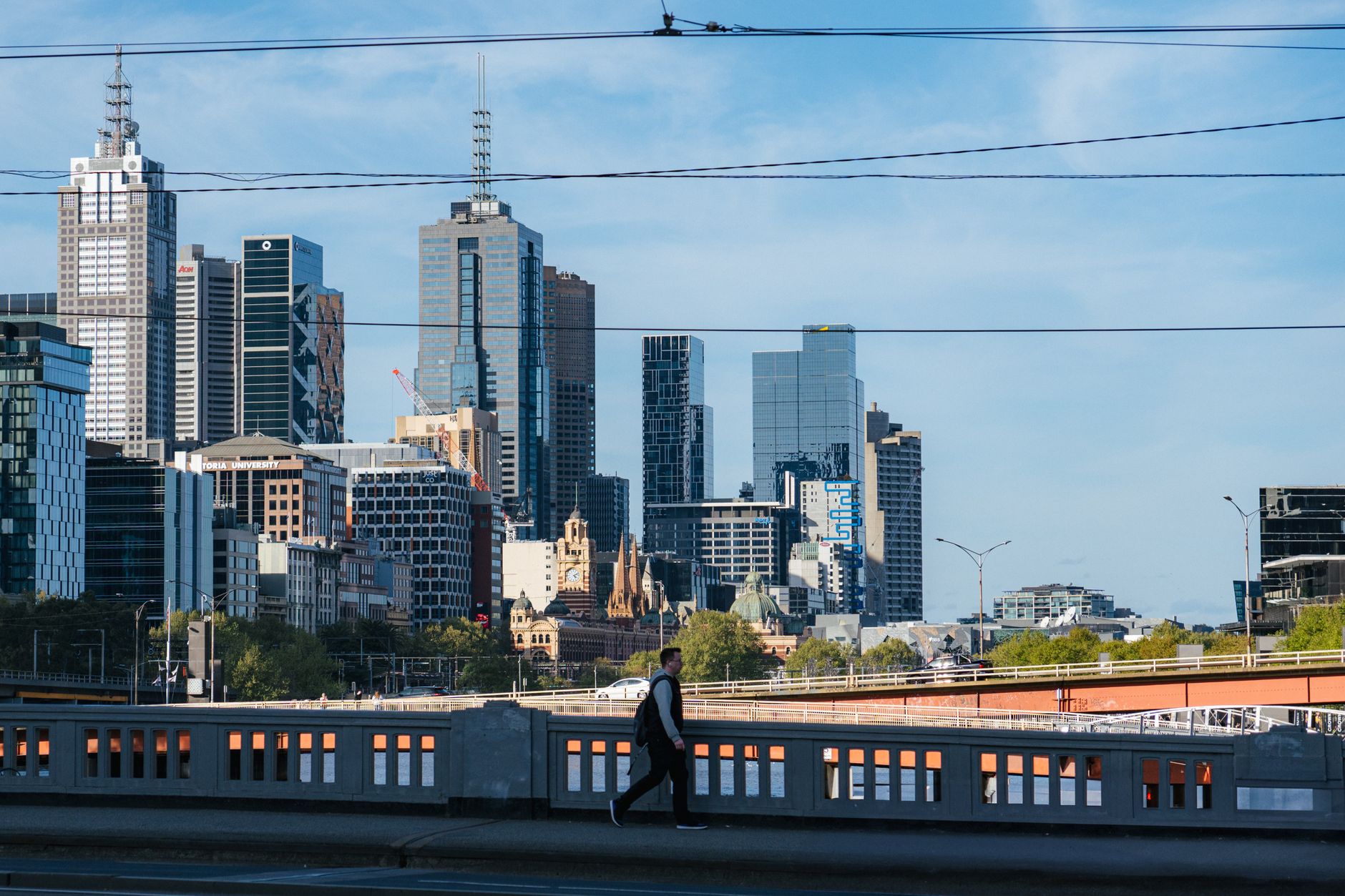 Dynamic shot of Melbourne's skyline with a pedestrian, showcasing urban life.