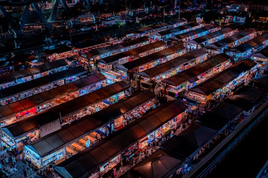 Vibrant aerial shot of a lively Bangkok night market with colorful stalls and bustling crowds.