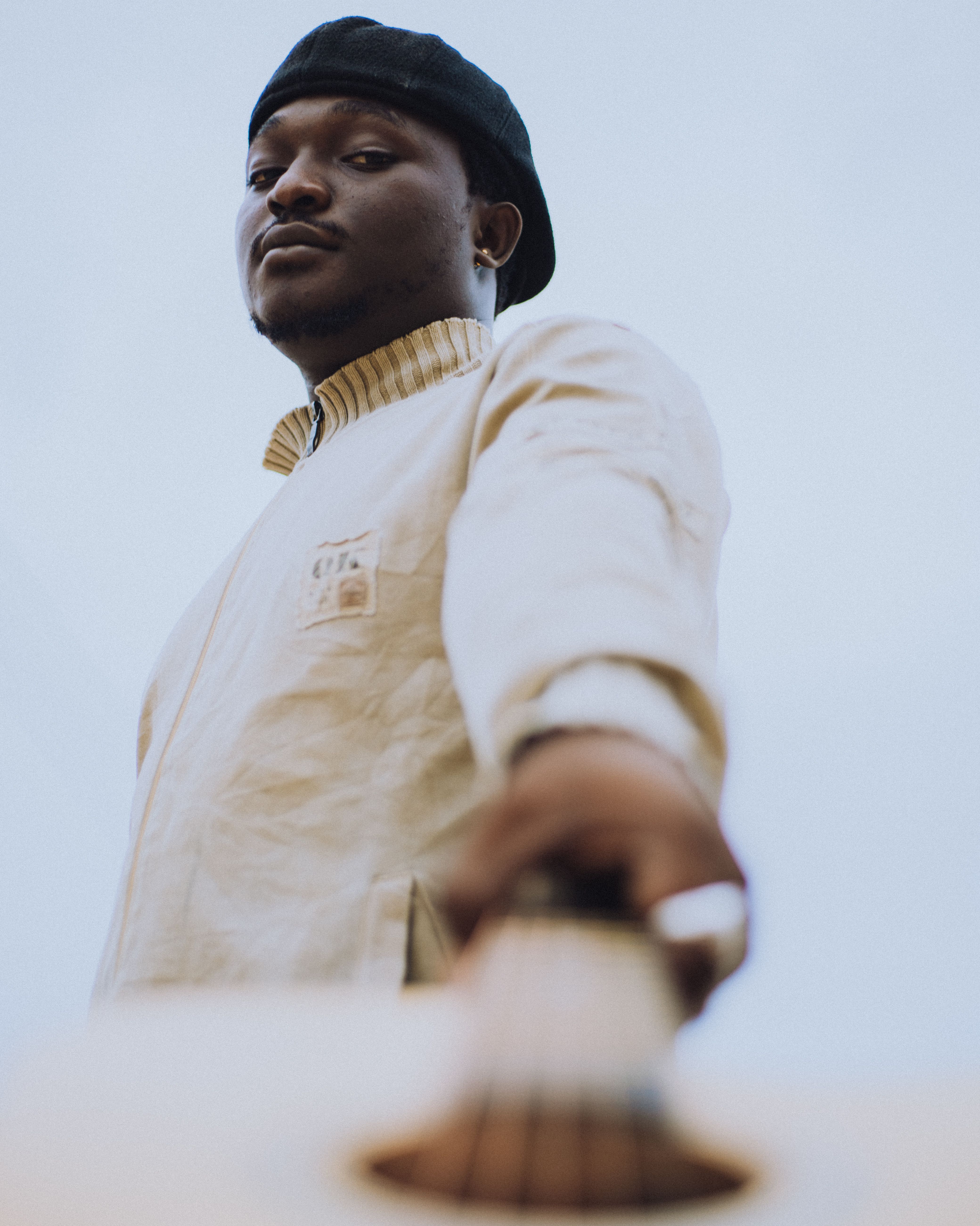 Young man in traditional attire holding a guitar in an outdoor setting.