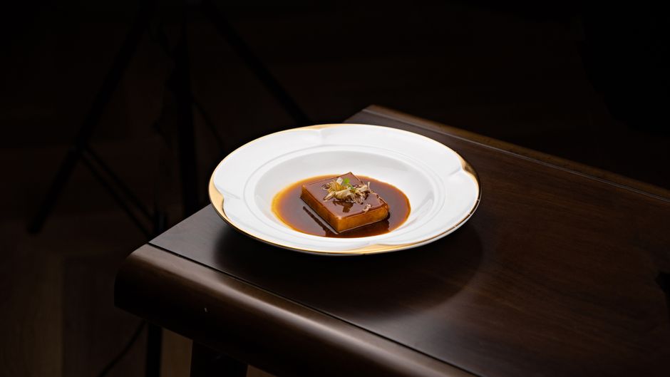 A skillet of sliced candied sweet potatoes glazed in a thick brown sugar and butter syrup, with a wooden spoon resting on the edge.