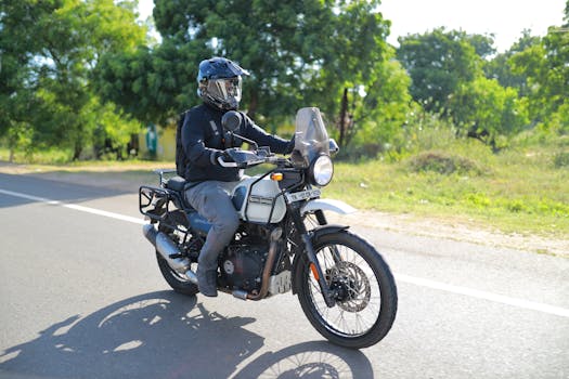 Biker on Royal Enfield cruising on a scenic road against a lush green backdrop.