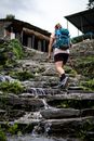 一名女子背着背包，手持登山杖，在风景优美的石道上徒步旅行
