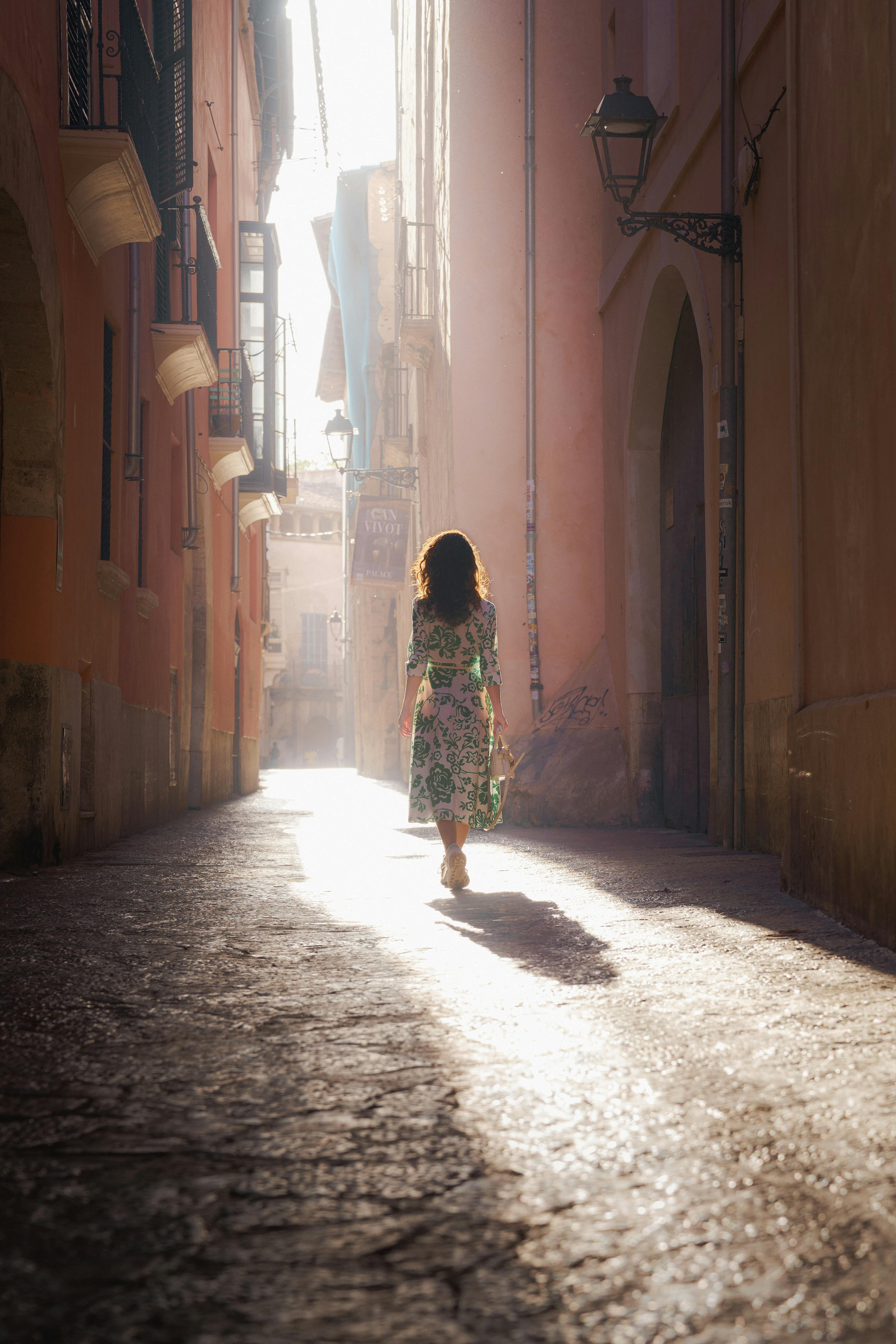 Woman Walking in Sunlit European Street Alley · Free Stock Photo