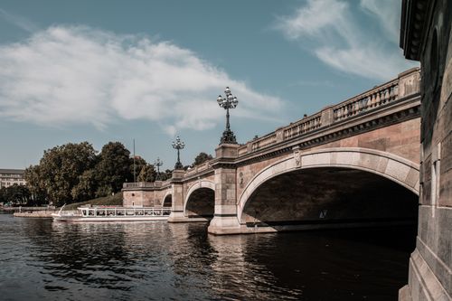 Free Elegant view of Hamburg's historic stone bridge over the Alster River, featuring a passing ferry. Stock Photo