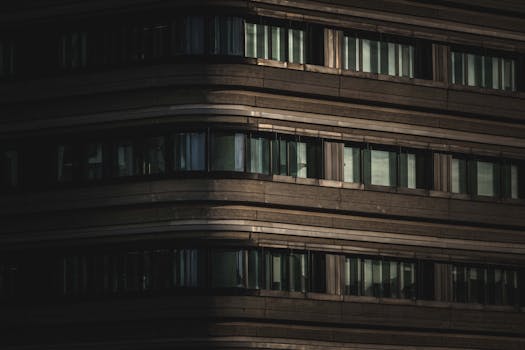 Close-up view of a modern building facade with minimal light. Dramatic urban architecture shot.