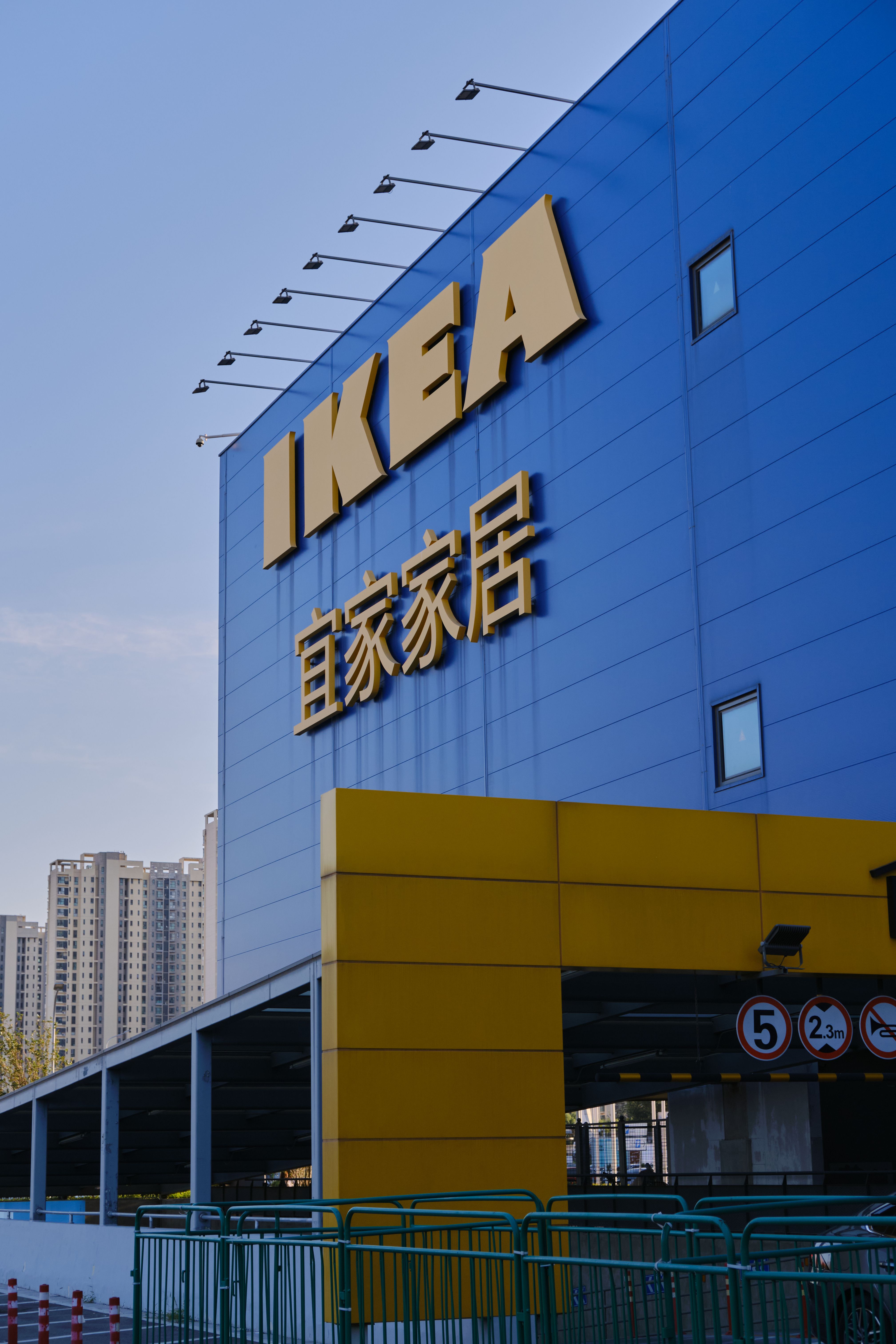 Blue and yellow IKEA store facade with skyscrapers in background.