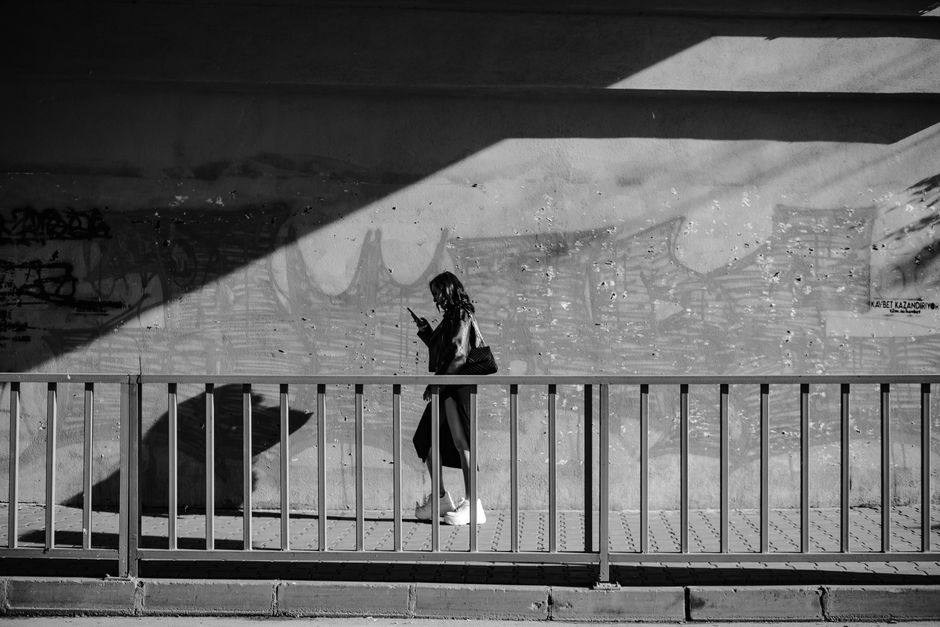 Black and white photo of woman walking under a bridge in Istanbul, Türkiye.
