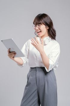 Excited young woman with headphones enjoying a video call on tablet.