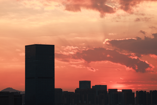 A stunning cityscape featuring skyscrapers silhouetted against a vibrant sunset.