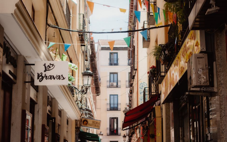 Encantadora calle de Madrid con banderas vibrantes y escaparates tradicionales.