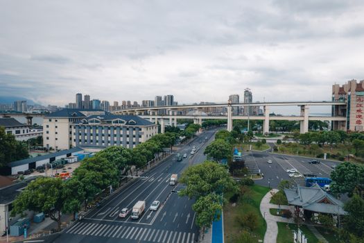 Aerial view of a cityscape with a highway, modern buildings, and greenery.