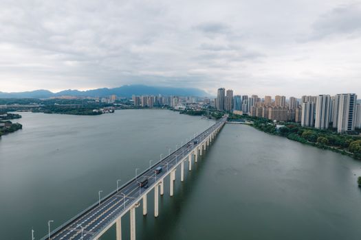 Stunning aerial shot of a bridge over water with Lu'an city skyline under cloudy skies.
