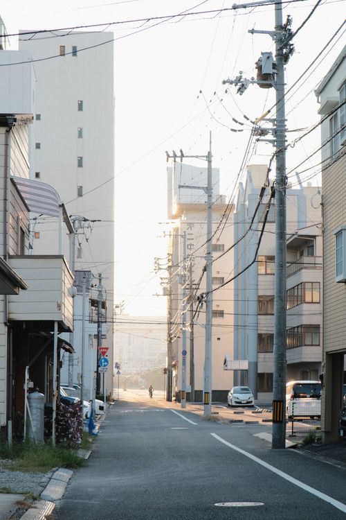 Free A quiet urban street bathed in early morning sunlight, showcasing residential buildings and empty roads. Stock Photo