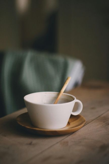 Warm ceramic coffee cup on a wooden table in a cozy setting.