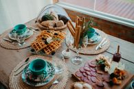 Inviting rustic breakfast setup with waffles, charcuterie, and bread on a wooden table.