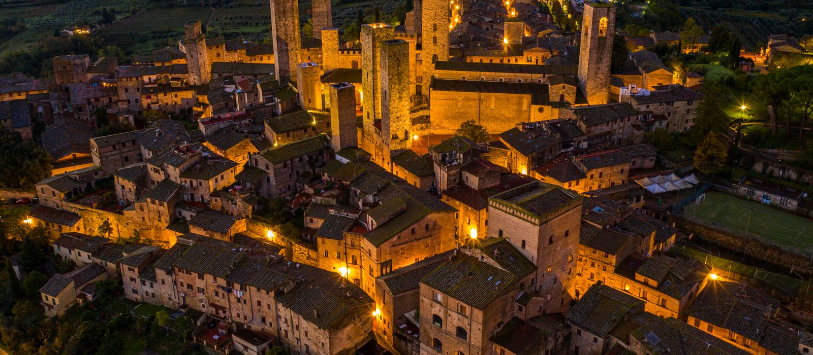 Captivating aerial view of San Gimignano's historic towers lit up at night, Italy.