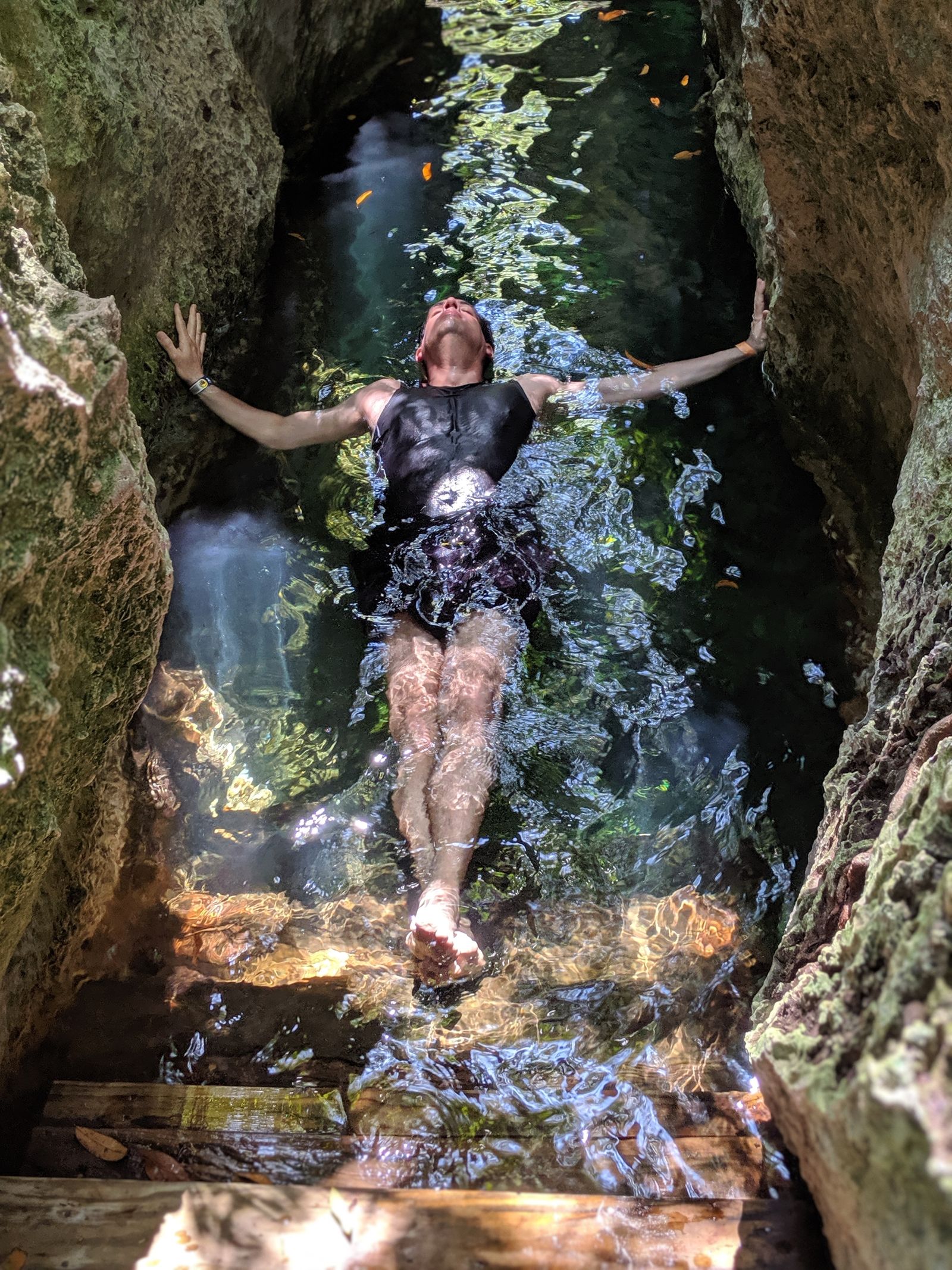 A swimmer relaxing in a natural rock pool cavern at a cenote