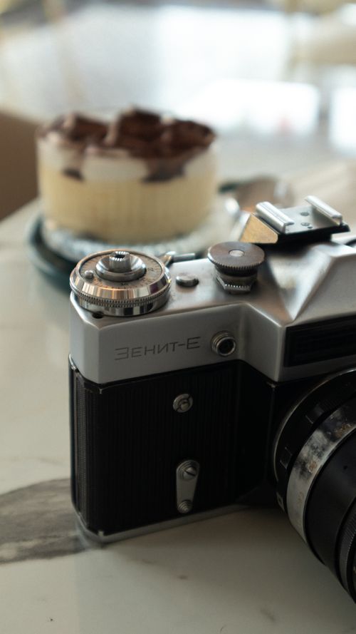 Free Close-up of a vintage camera on a café table with a dessert in the background. Stock Photo