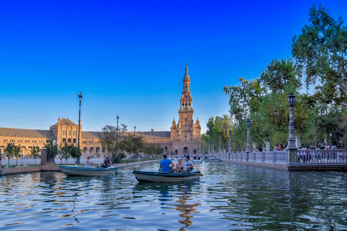 Bărci pe canalul din Plaza de España din Sevilla, cu vizitatori pe mal