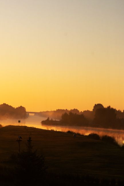 Beautiful river scenery at sunrise with mist, trees, and a calm atmosphere.