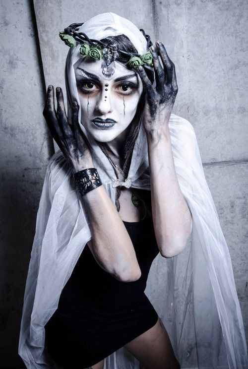 Free Artistic portrait of a woman with spooky Halloween makeup, dark clothing, and a white veil. Stock Photo