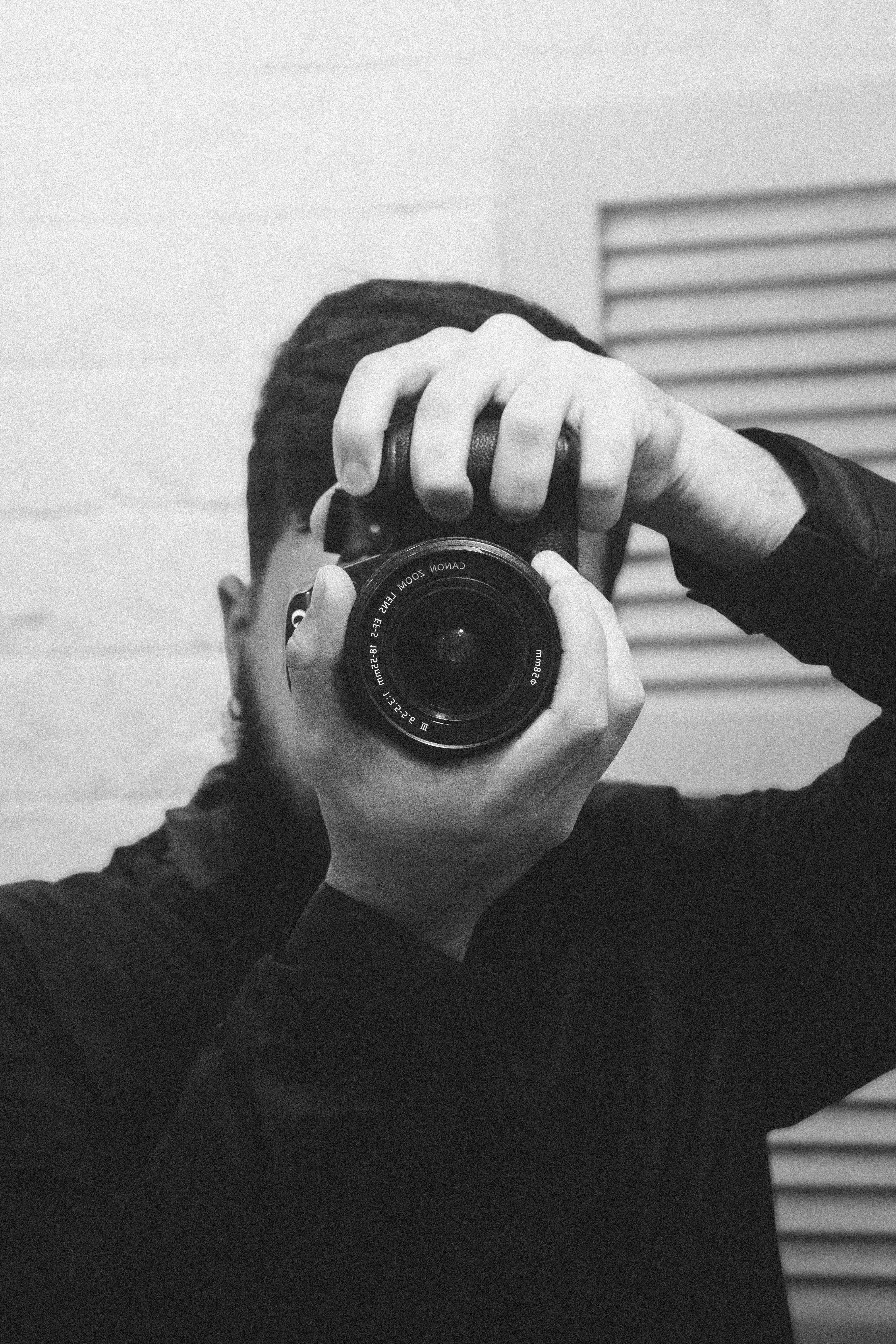 Monochrome portrait capturing a photographer in action with a camera.