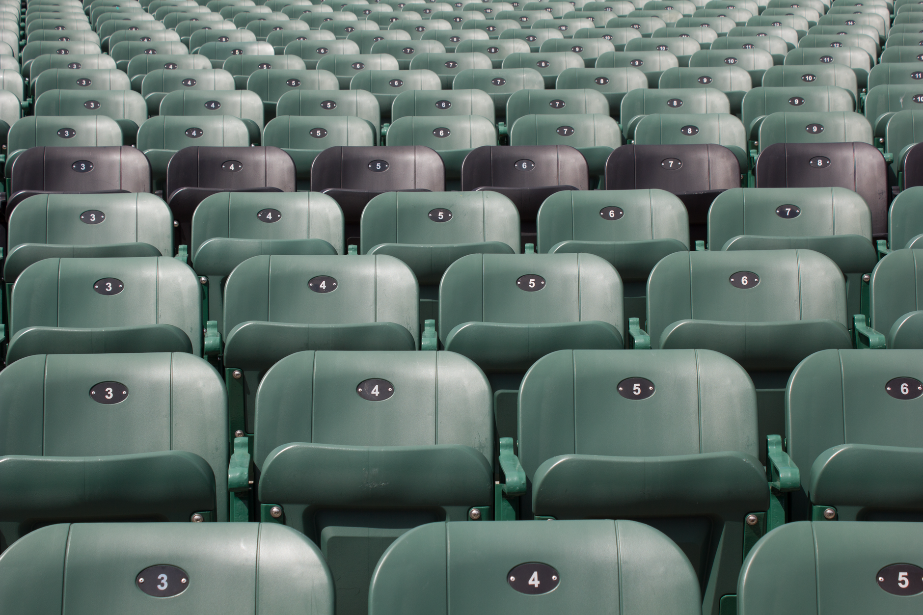 Rows of empty green stadium seats with unique numbers in Québec, Canada.