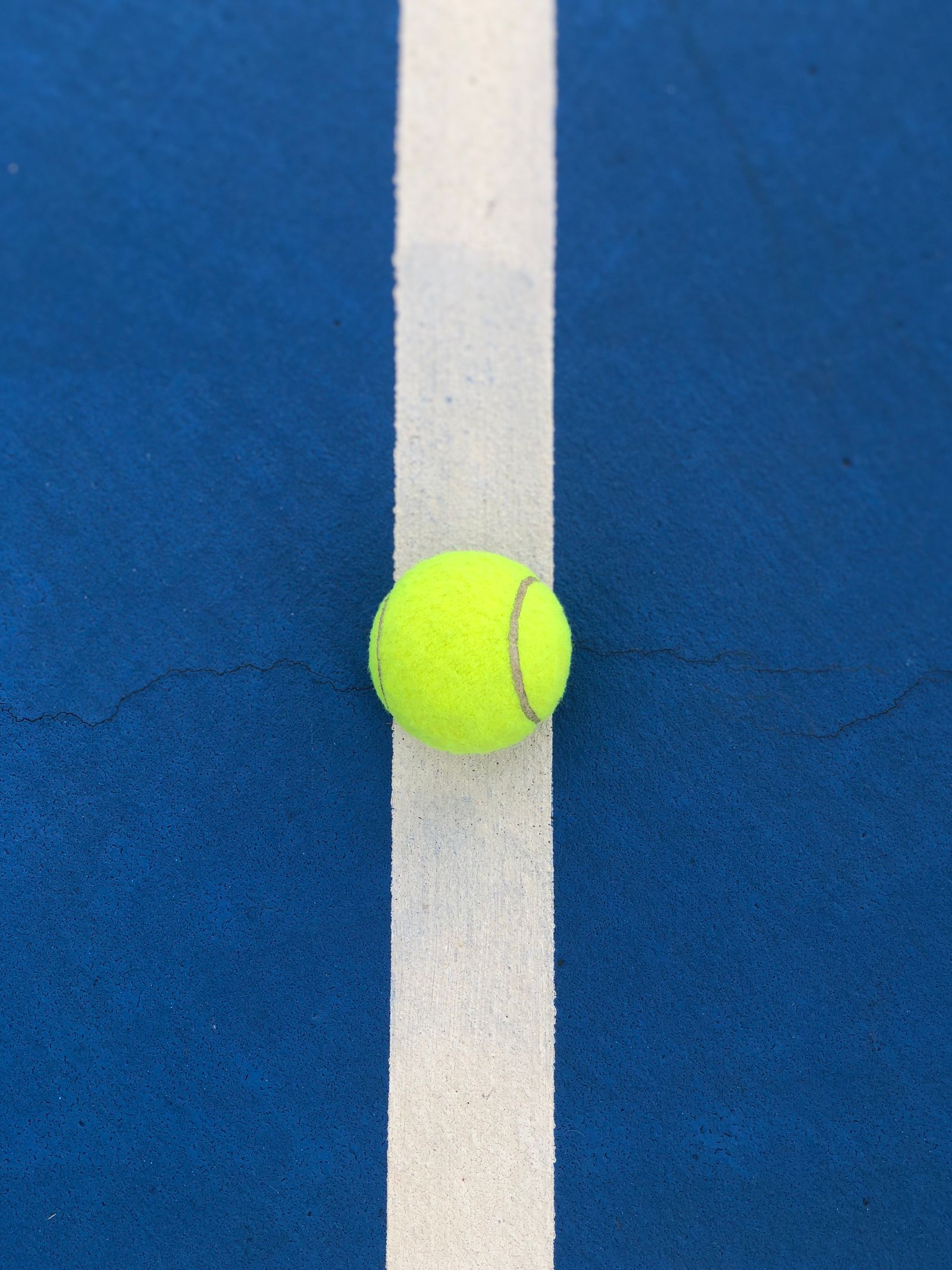 Tennis ball positioned precisely on a white court line